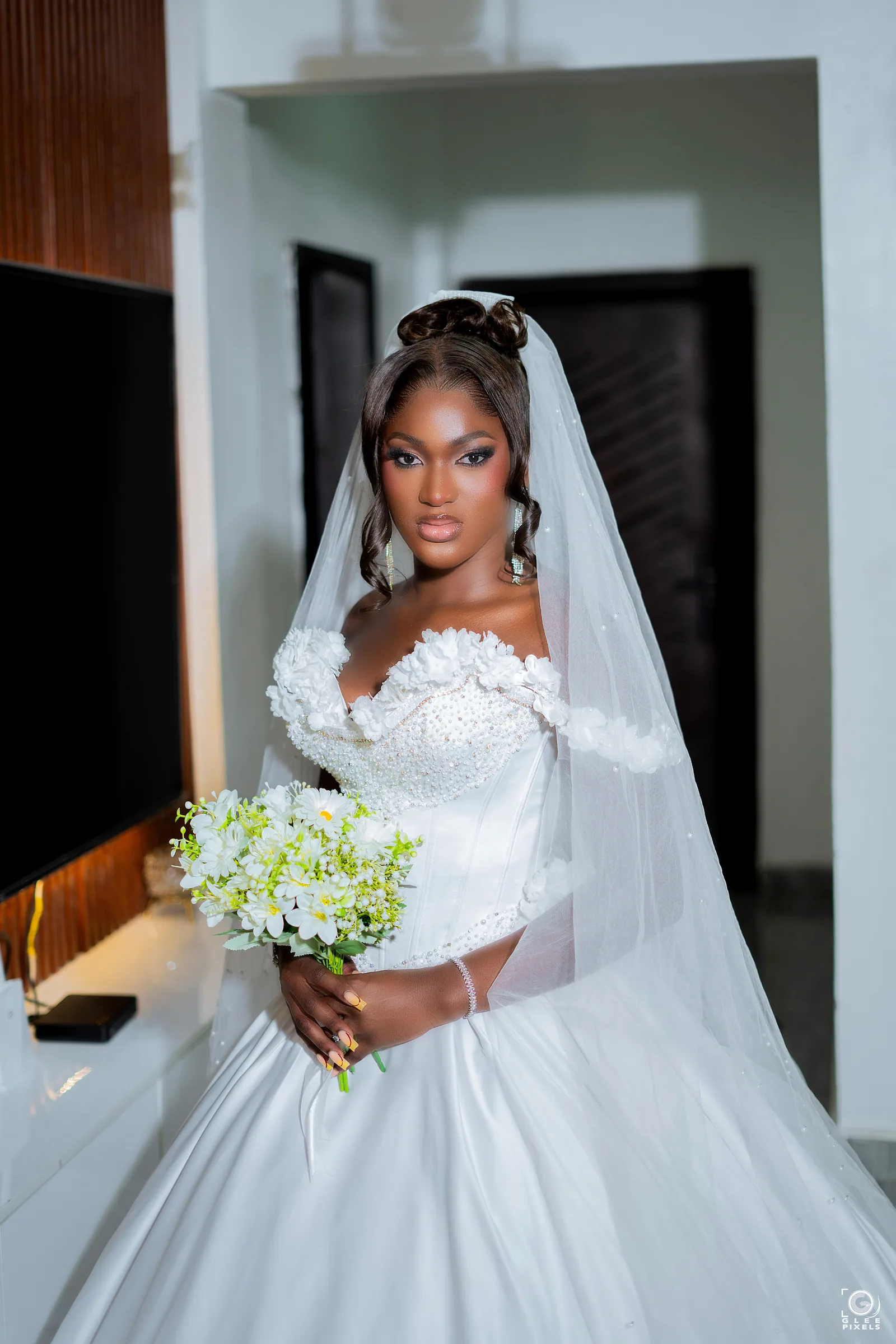 Close bridal portrait of a Magmens Couture gown showing a sculpted off-shoulder bodice of hand-applied floral lace and beaded detailing.
